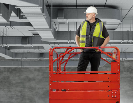HVAC installation. Building engineer inspects ventilation ductwork from aerial work platform during commercial facility construction.