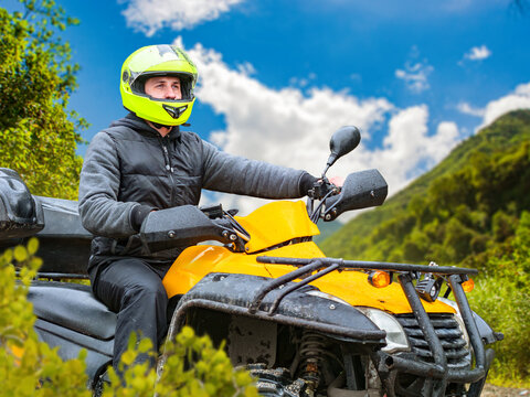 Adventure tourism. ATV rider explores mountain trails wearing protective helmet during off-road recreational journey.