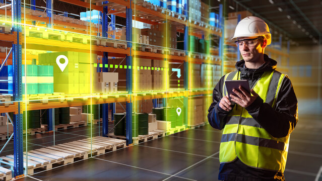 Warehouse logistics center. Inventory manager uses tablet to track goods location and monitor automated storage operations in smart warehouse.