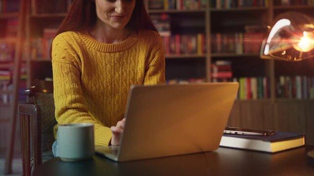 Smiling female freelancer typing on laptop in cozy urban library, working online