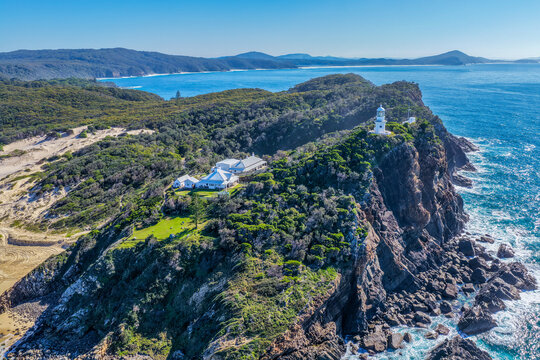 Aerial view of the historic Seal Rocks Lighthouse overlooking the rugged coastline, deep blue ocean and surrounding coastal landscape at Seal Rocks, NSW, Australia.