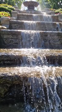 Cascading Water Over Stone Steps in Outdoor Fountain - A multi-tiered outdoor fountain features water cascading over rough stone steps, creating a dynamic and refreshing display.