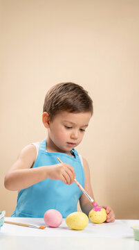 Young caucasian male child painting colorful easter eggs at table