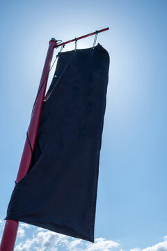 Backlit black fabric banner on red pole under blue sky, Lake Kawaguchi, Fujikawaguchiko, Japan