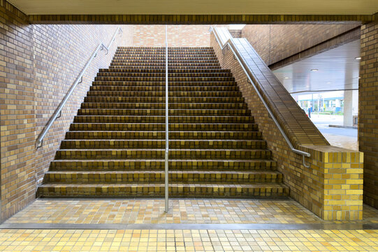 Tiled staircase with metal rails in brick underground passage, Tokyo, Japan, front view