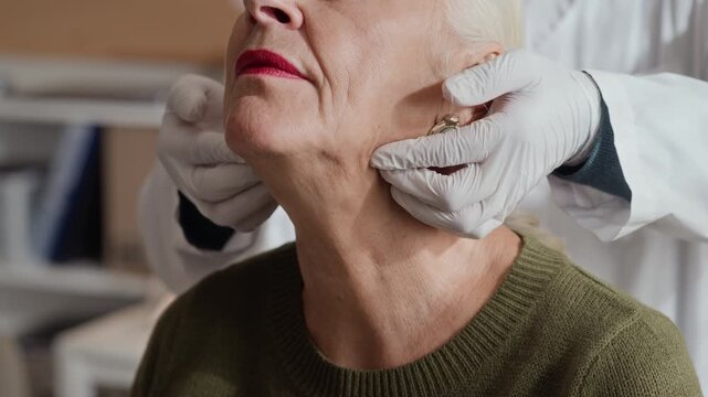 Senior Caucasian female patient undergoing neck lymph node examination by doctor in gloves. Clip is perfect for geriatric healthcare and medical clinic advertising
