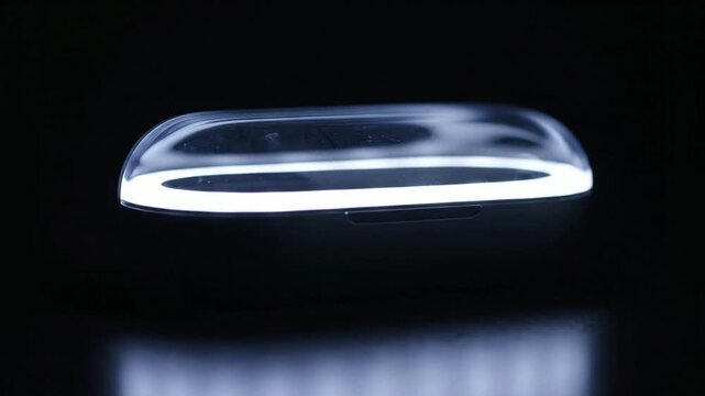 Modern wireless earbuds charging case with glowing led indicator light in dark studio setting, sleek tech accessory for music and communication