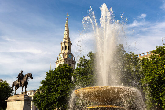 Trafalgar Square fountain with Saint Martin in the Fields church and George IV statue at sunset in London, England, UK