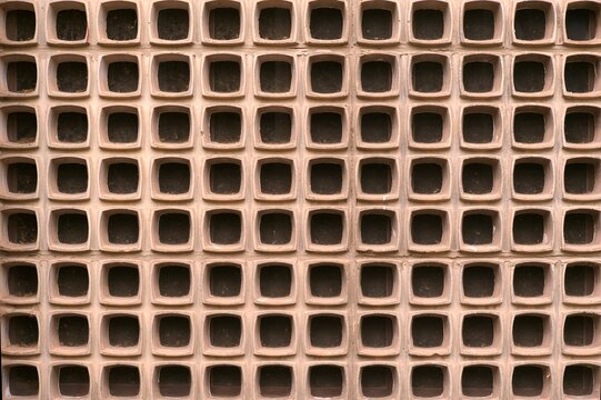 Symmetrical geometric breeze block wall pattern with repeating square lattice structure and warm terracotta tone