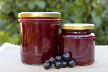 Jars of homemade berry jam placed on a cloth with fresh berries beside them © BoTanya