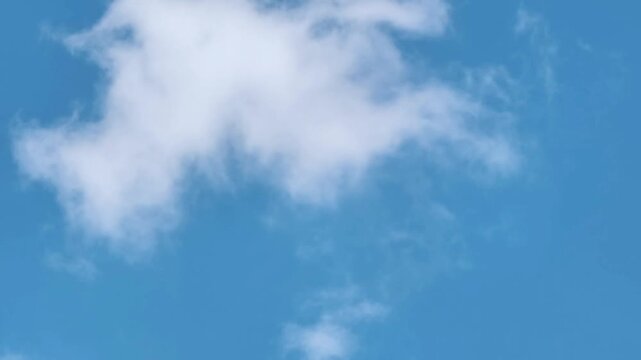 A picturesque view of the serene blue sky adorned with soft, ethereal white clouds, evoking feelings of tranquility and boundless space on a bright day