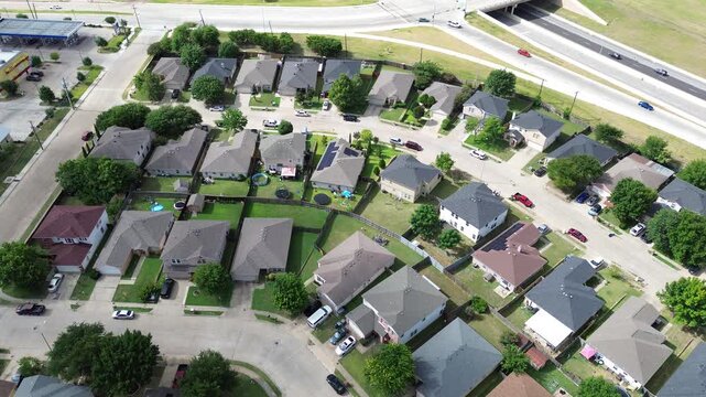 Winding subdivision streets border commercial lots elevated highway overpasses, showcasing high density housing single family configurations within Pleasant Grove, Dallas Fort Worth suburbs, Texas