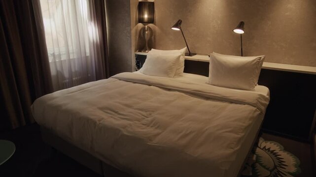 No people establishing shot of empty double bed with linens illuminated by bedside lamps in hotel room, perfect for travel agency promotions, hotel booking websites or real estate listings