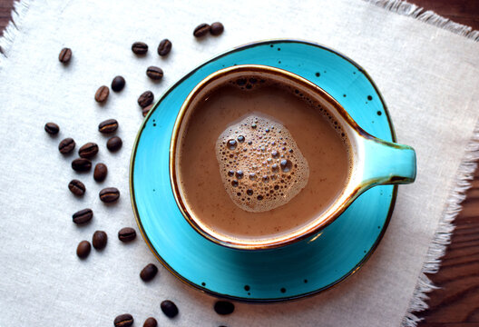 Coffee with milk in a beautiful blue ceramic cup on a wooden table. Cup of coffee, coffee beans.