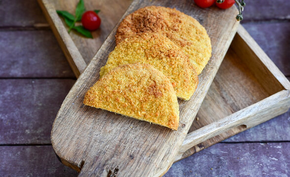 Crispy  deep fried   chicken  burgers . Breaded  with cornflakes chicken  breast fillets  with  french fires and fresh    aragula on wooden rustic background