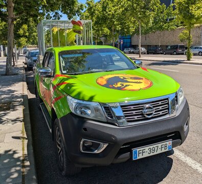 Furgoneta pickup con est&eacute;tica de Jurassic World, anunciando una exposici&oacute;n de dinosaurios, con una jaula met&aacute;lica que transporta un Dilophosaurus de tama&ntilde;o real, Madrid, Espa&ntilde;a, 21 de mayo de 2026