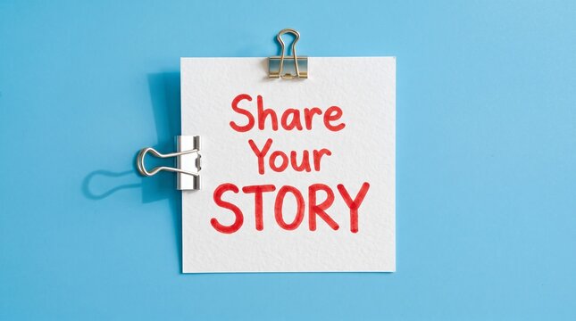 Share Your Story message on white paper note, storytelling concept with binder clips on blue background, creative narrative and testimonial marketing