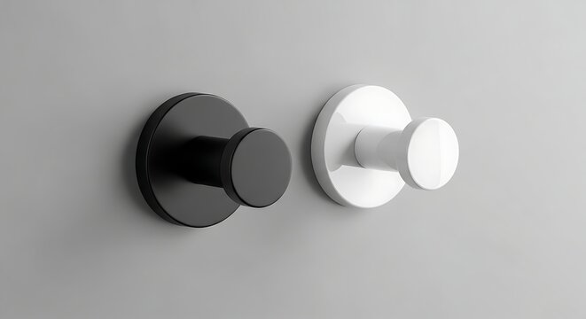 Two circular wall mounted pegs for hanging coats and accessories positioned on a painted partition showcasing contrasting dark and light finishes for a contemporary interior design theme