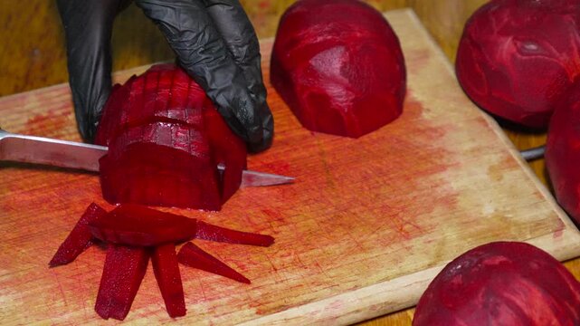 Beetroot slicing, chef cutting fresh organic vegetable cubes on a wooden board. Static high-angle shot.