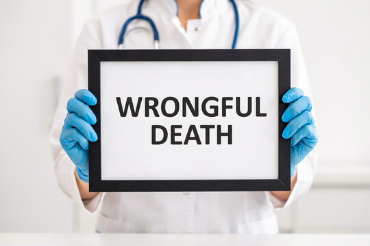 Doctor's hands in blue gloves holding a framed sign with 'Wrongful Death' text during a studio session