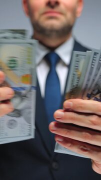 Formally dressed man is counting US Dollar bills, close-up.