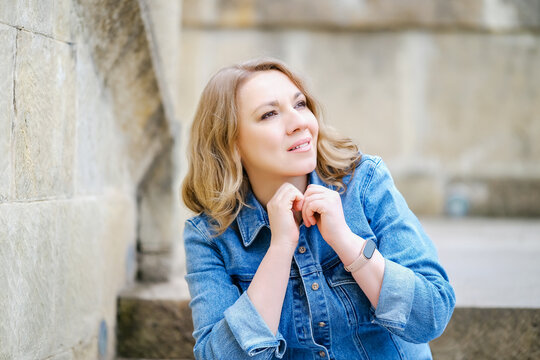 Peaceful wavy haired woman sitting on stone steps and dreaming. Concept of mindfulness, reflection and serene mood.