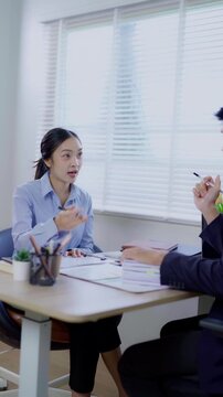Two business women are sitting and talking in the office and discussing projects on laptops and graphs working together in the office.