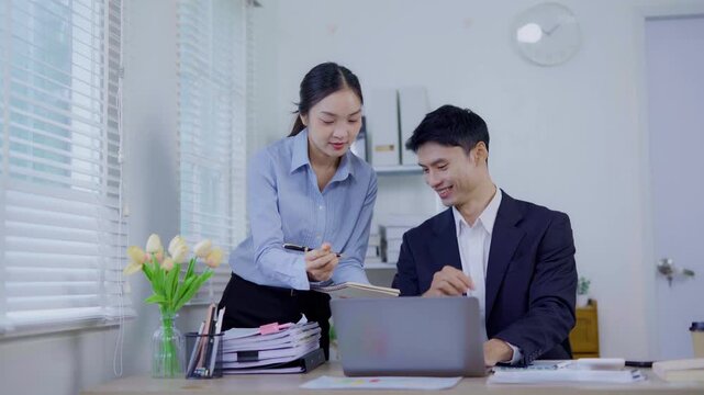 Two business women are sitting and talking in the office and discussing projects on laptops and graphs working together in the office.