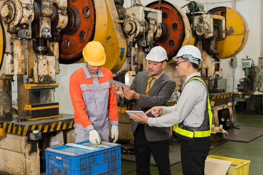 Manager and engineer reviewing stamped metal bracket with young press operator