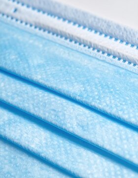 Close-up of stacked blue protective facial coverings with white seams