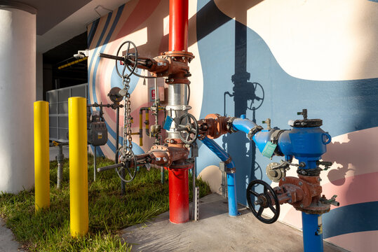 Fire hydrant shutoff valves and pipes against colorful mural wall