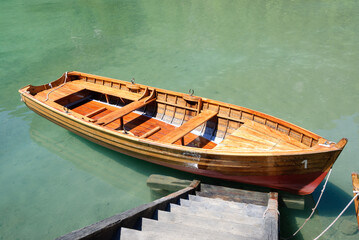 Traditional wooden rowboat moored on crystal-clear turquoise lake with dock and calm water. Peaceful outdoor scene ideal for travel, recreation, nature and summer themes. © giemmephoto