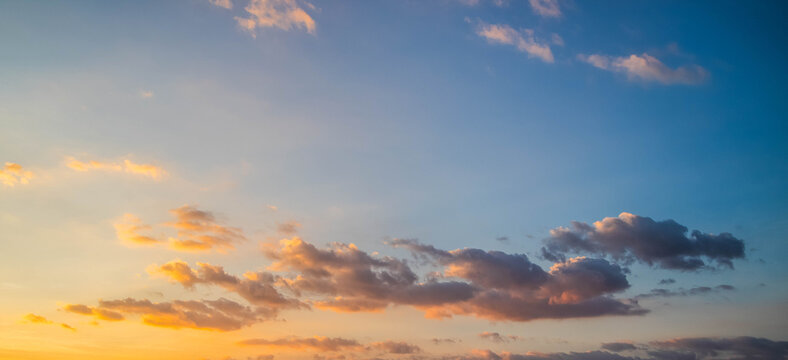 Beautiful sunset sky with soft clouds and vivid blue to orange gradient background.Panoramic sky background during golden hour sunrise with colorful clouds and copy space.