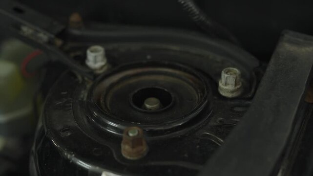 Close-up of front shock absorber strut tower mount with bolts.