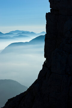 Mountain cliff silhouette overlooking misty alpine valleys, perfect for tourism exploration in nature with sky copy space, Julian Alps Natural Park,Alba Valley,Friuli Venezia Giulia,Italy.