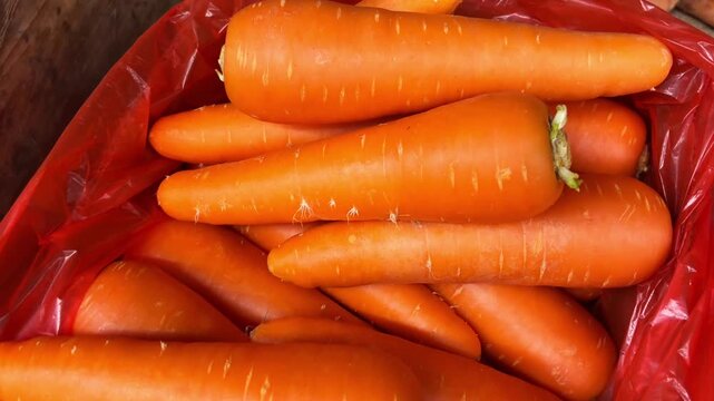 Fresh unpeeled organic carrots stacked on a wooden supermarket counter, healthy vegetables market retail concept