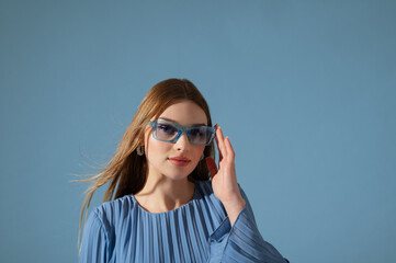 Beautiful fashionable woman wearing trendy blue color sunglasses, stylish pleated dress. Close up studio portrait. Copy, empty space for text © Victoria Fox