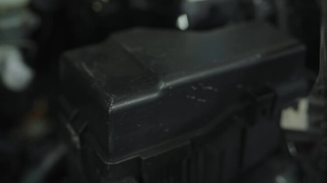 Black plastic car fuse and relay box under vehicle engine hood.