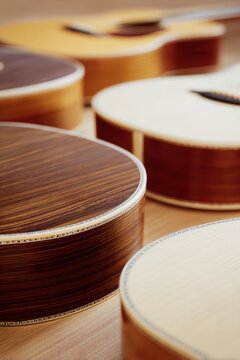 Assorted acoustic guitar bodies wooden soundboards close up with rich wood grain for musical instrument design mockup and background
