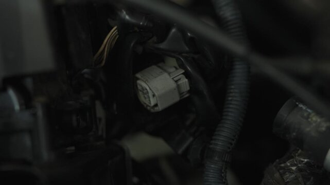 White plastic wire harness connector plug hidden inside engine bay.
