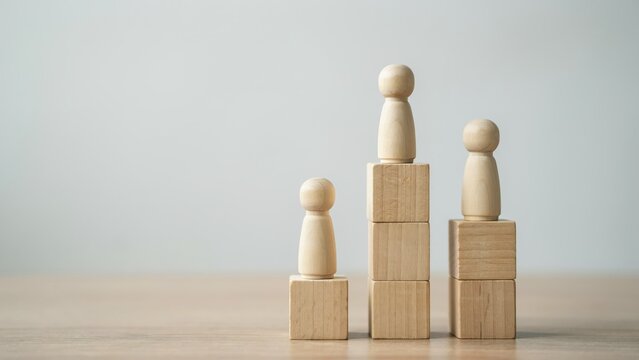 Wooden doll figures standing on top of stacked wooden blocks representing a ranking