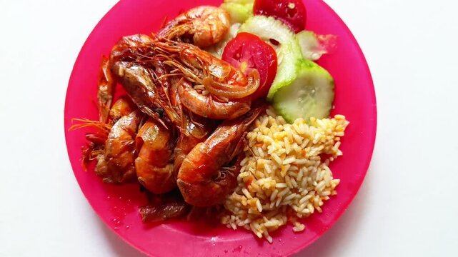 Plate of cooked fried shrimp served with rice and fresh cucumber tomato salad for typical traditional dish from Guatemala