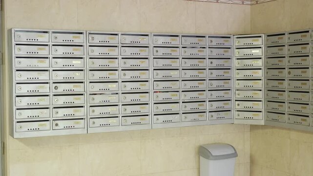 Series of three frames showing a row of silver mailboxes arranged in a corner of a hallway with beige walls and a trash bin positioned nearby