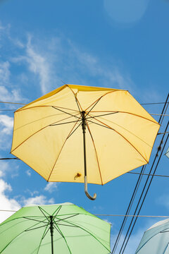 Yellow umbrella photographed from a low angle perspective against a clear blue sky. Minimalist image with vibrant colors and ample copy space