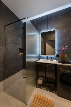 Modern Dark Bathroom Interior with Shower, Illuminated Mirror, and Stylish Vanity Cabinet