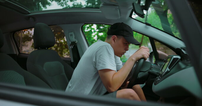 Young man gripping steering wheel tightly, sitting tensely in driver&rsquo;s seat with anxious expression, conveying stress, nervousness, and inner tension