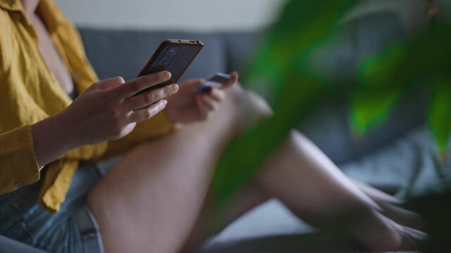 Woman holding credit card and smartphone for online mobile payment.