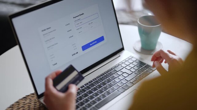 Woman paying online using credit card and laptop at home.