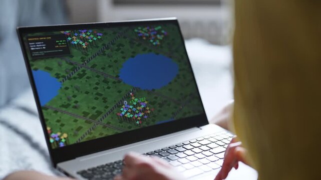 Woman playing economic strategy game on laptop.