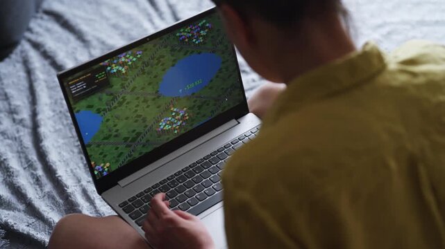 Woman playing economic strategy game on laptop.